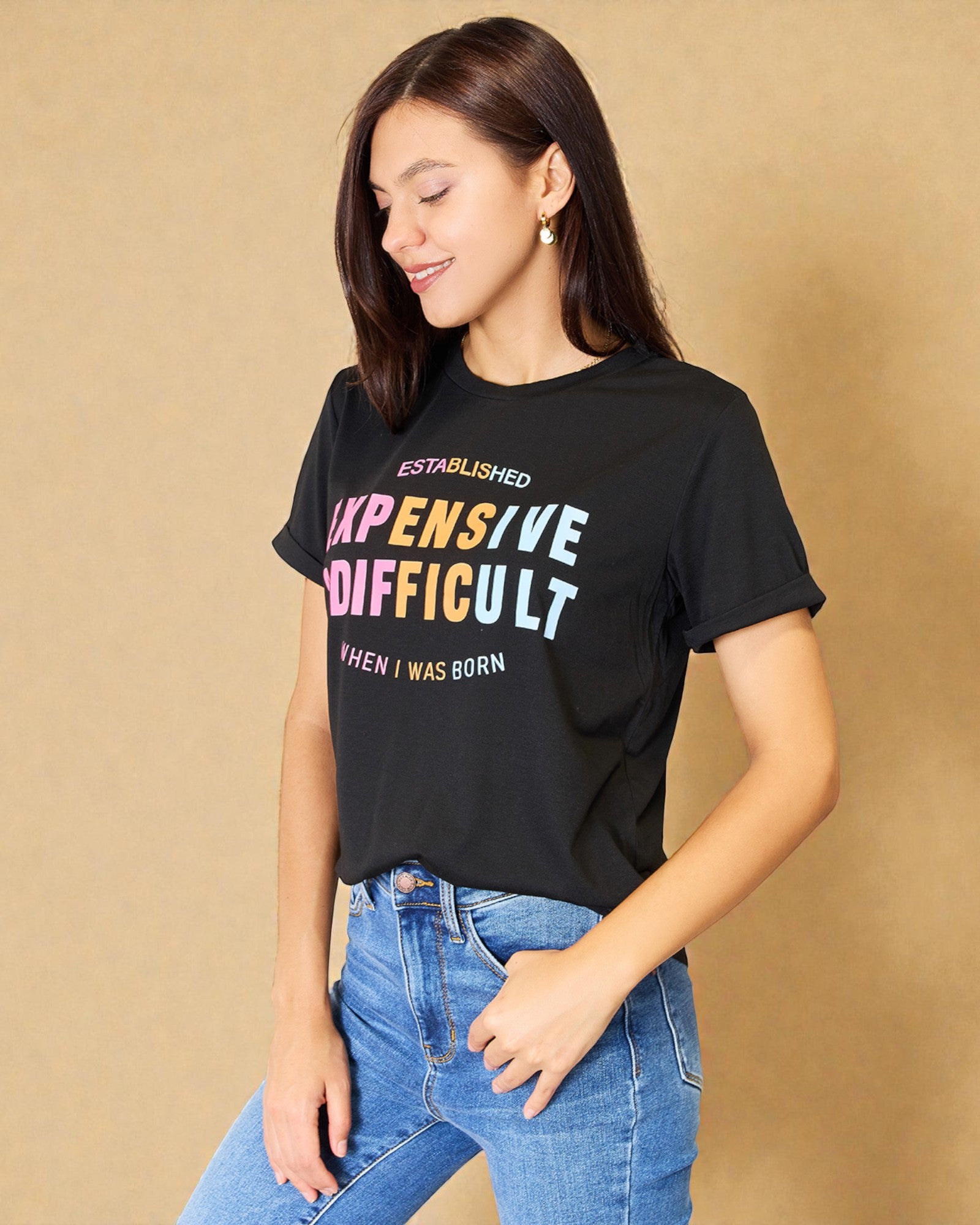 Woman wearing a black t-shirt with colorful text on a beige background