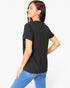 A woman wearing a black short-sleeve t-shirt and blue jeans, shown from a three-quarters back view against a plain white studio background.