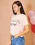 Woman wearing a pink t-shirt with text, standing against a beige background with balloons.