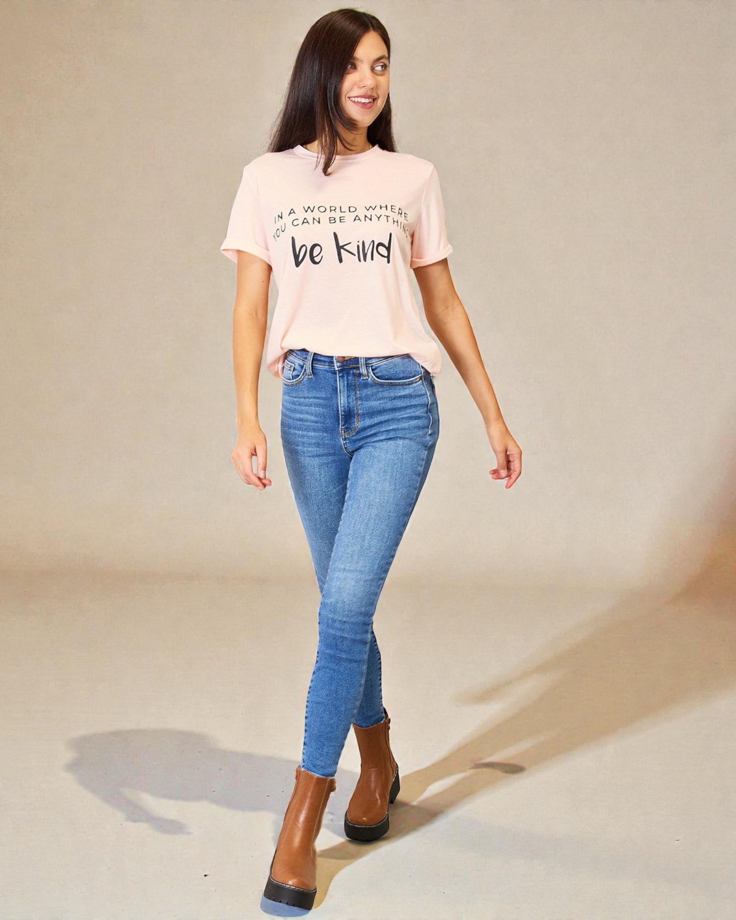 Woman wearing a pink t-shirt and blue jeans on a plain background