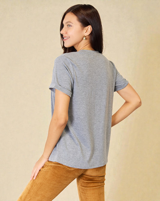 Woman wearing a gray t-shirt and brown pants against a beige background
