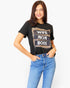 A woman modeling a black graphic t-shirt with a leopard print and white text reading 'WIFE MOM BOSS', paired with blue jeans, against a plain white background.
