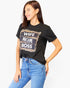 A woman wearing a black graphic t-shirt with a leopard print and white text that reads 'WIFE MOM BOSS', paired with blue jeans, against a plain white background.