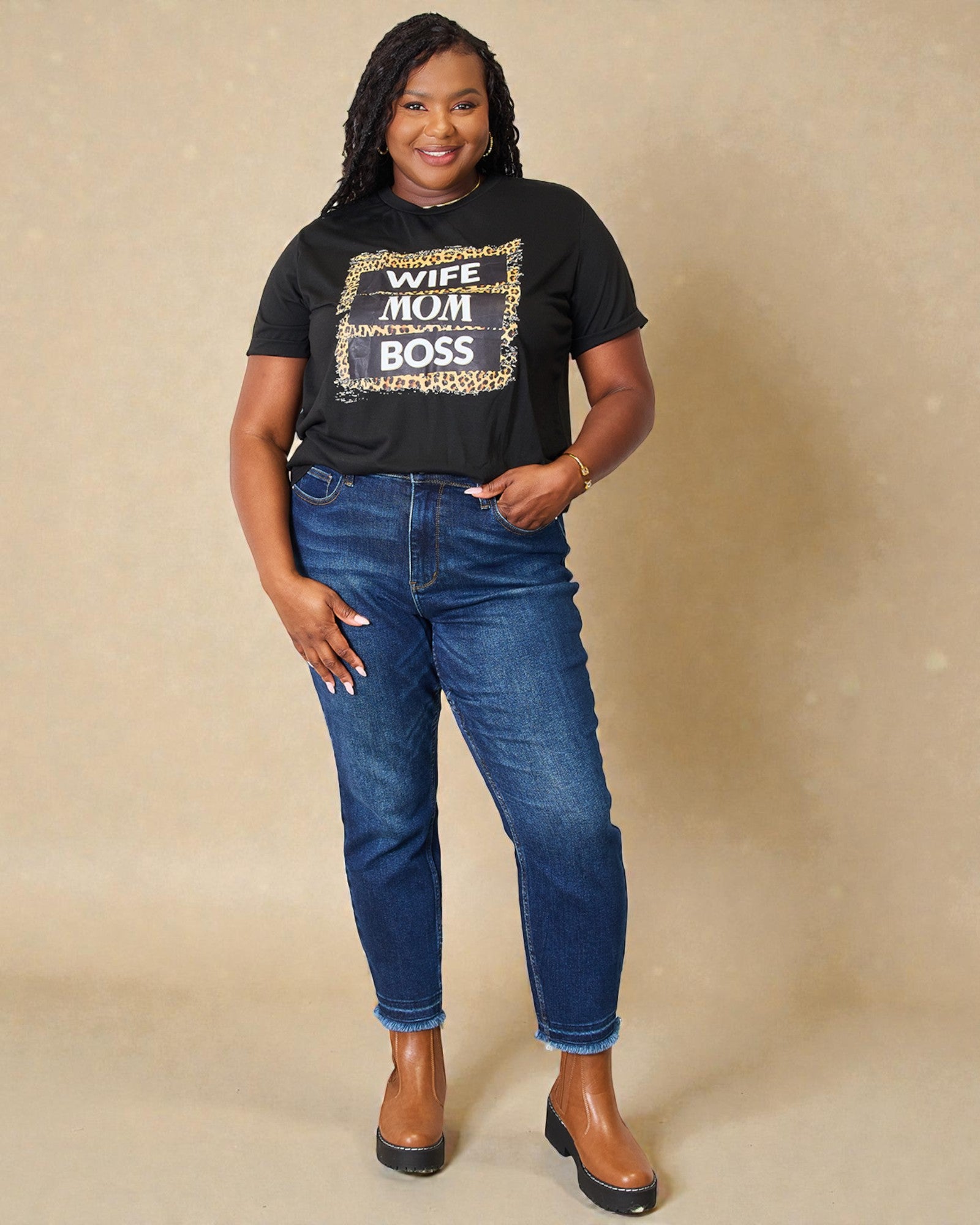 Woman wearing a black t-shirt with text and blue jeans on a beige background