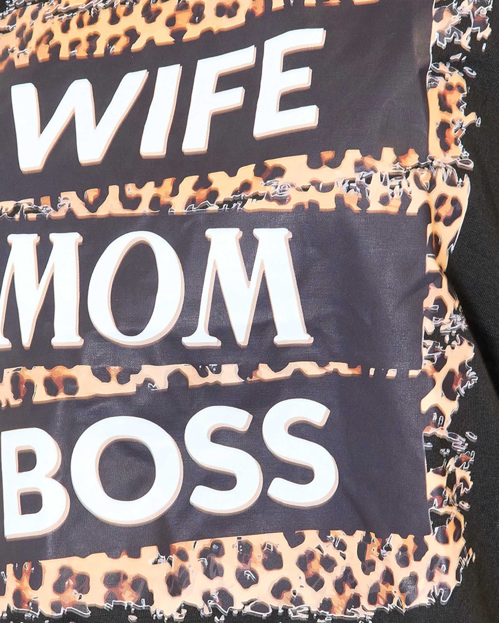 Close-up of a garment featuring the words 'WIFE', 'MOM', and 'BOSS' in large white letters on black panels, layered with leopard print fabric.
