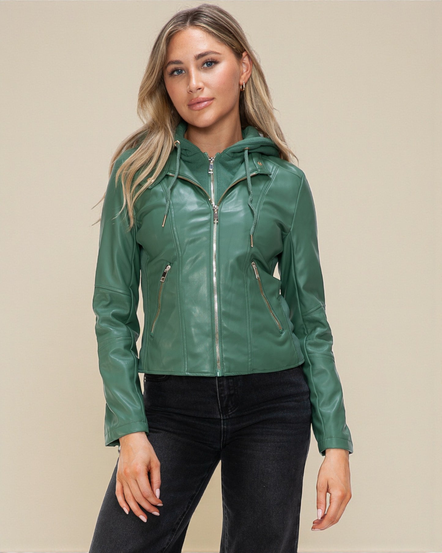 Woman wearing a green leather jacket against a beige background
