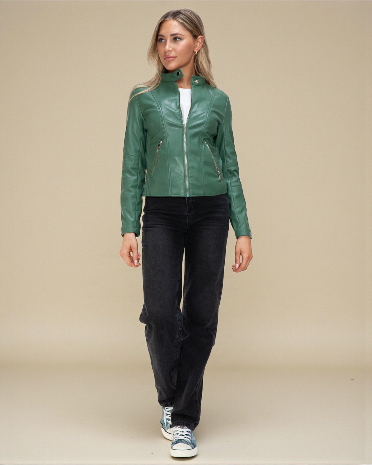 Woman wearing a green leather jacket and black pants on a beige background