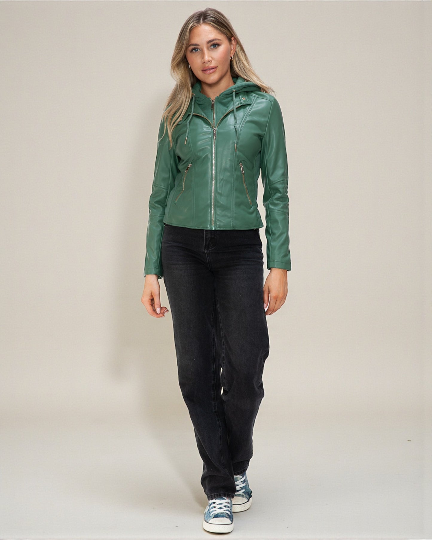 Woman wearing a green jacket and black pants on a plain background