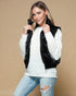 Woman wearing a white sweater with a black puffer vest against a beige background