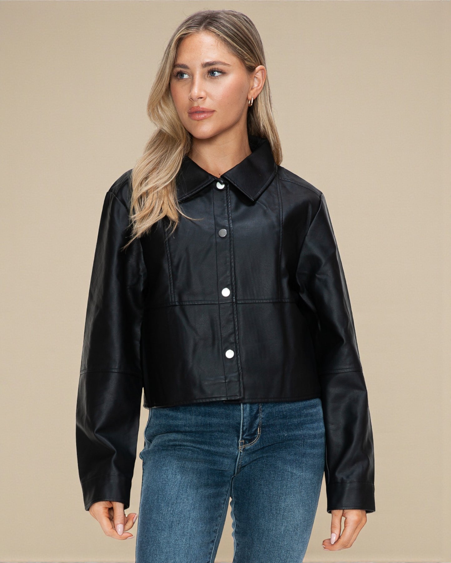 Woman wearing a black jacket and blue jeans on a beige background