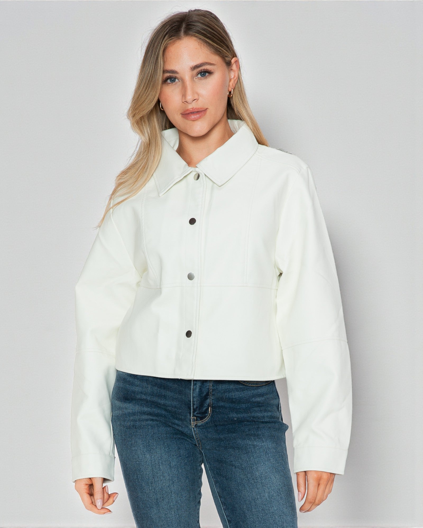 Woman wearing a white shirt and blue jeans on a plain background