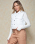 Woman wearing a white puffer vest over a white shirt with beige pants against a beige background