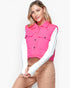 A woman wearing a bright pink quilted sleeveless puffer vest over a white long-sleeve shirt and tan pants, posed against a clean white studio background.