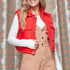 Person wearing a red puffer vest over a white long-sleeve shirt and beige overalls against a patterned background.