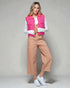 Woman wearing a pink vest, white shirt, tan pants, and white sneakers on a gray background