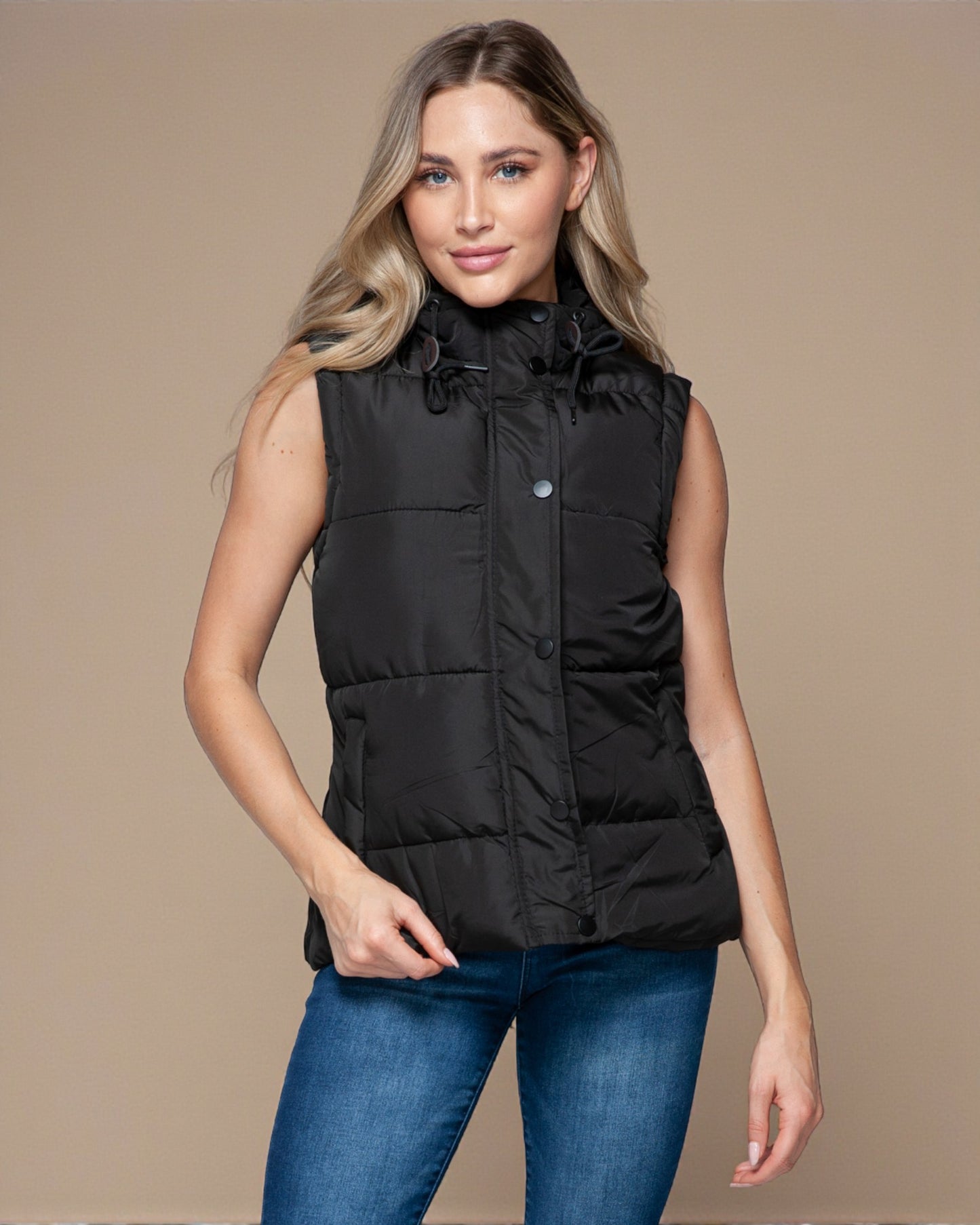 Woman wearing a black puffer vest against a beige background