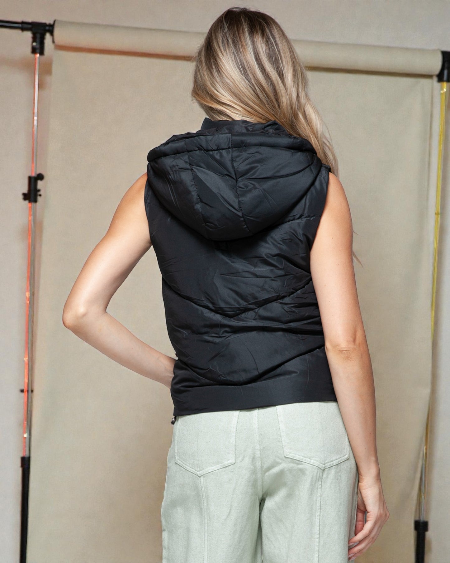Person wearing a black sleeveless hooded puffer vest against a neutral background