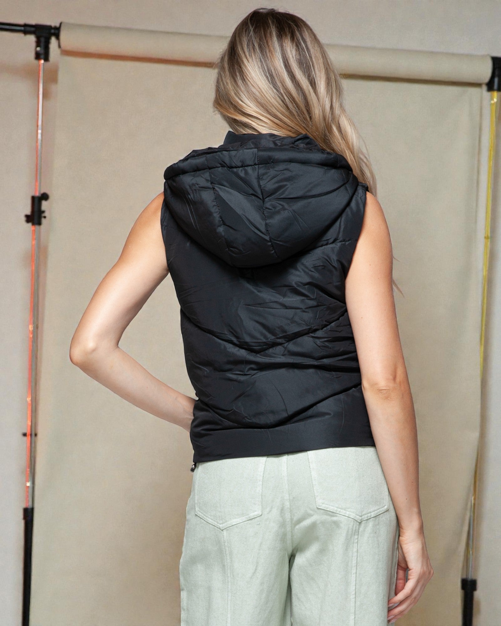 Person wearing a black sleeveless hooded puffer vest against a neutral background