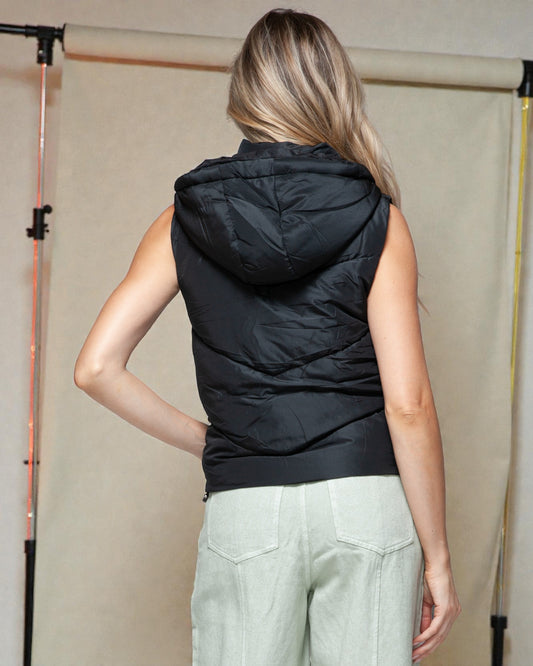 Person wearing a black sleeveless hooded puffer vest against a neutral background