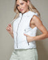Woman wearing a white puffer vest against a beige background