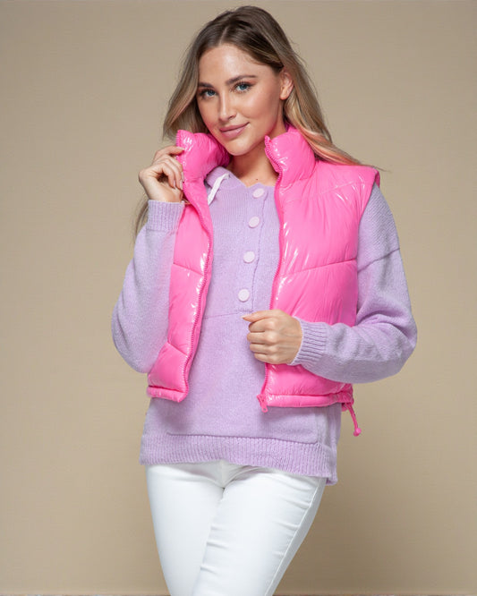 Woman wearing a pink puffer vest over a purple sweater on a beige background