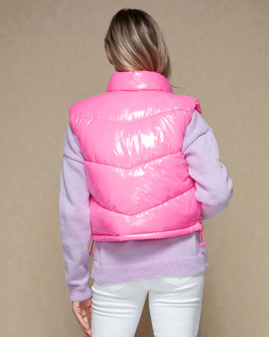 Person wearing a pink puffer vest over a light purple sweater on a beige background
