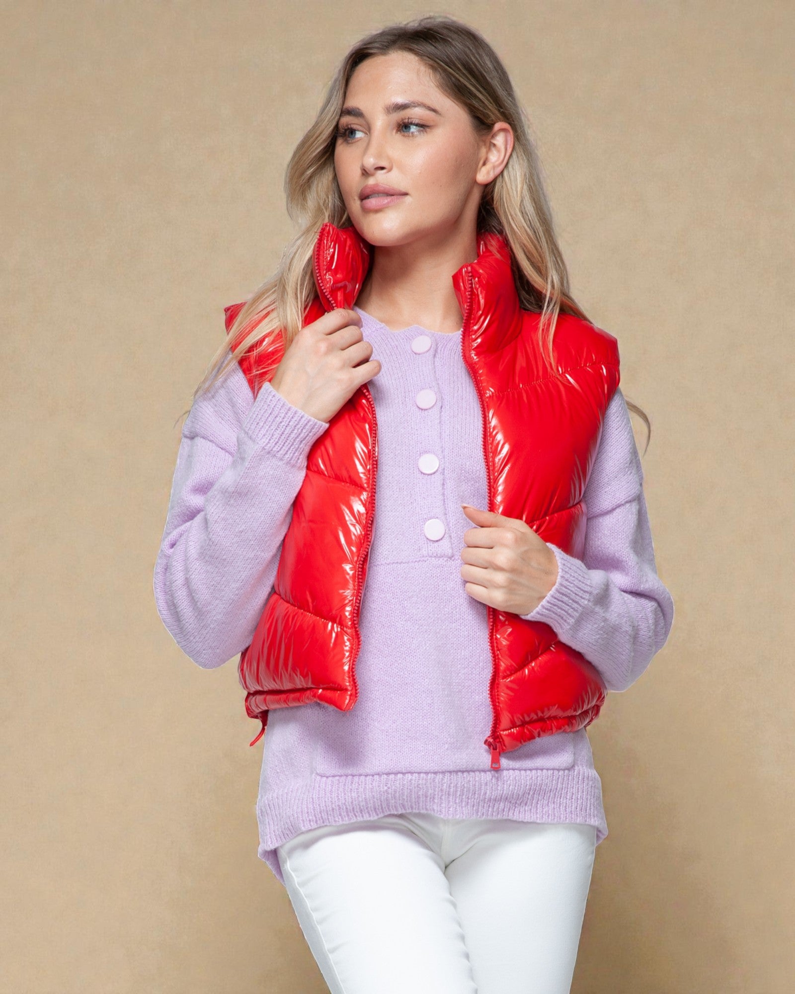 Woman wearing a red puffer vest over a light purple sweater on a beige background