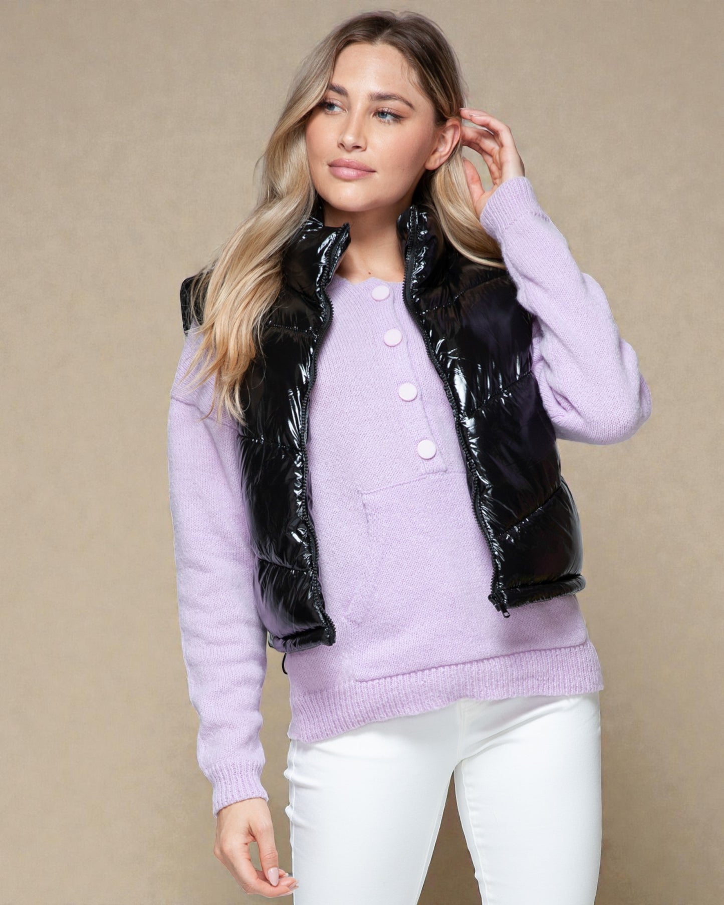 Woman wearing a lavender sweater with a black puffer vest on a beige background