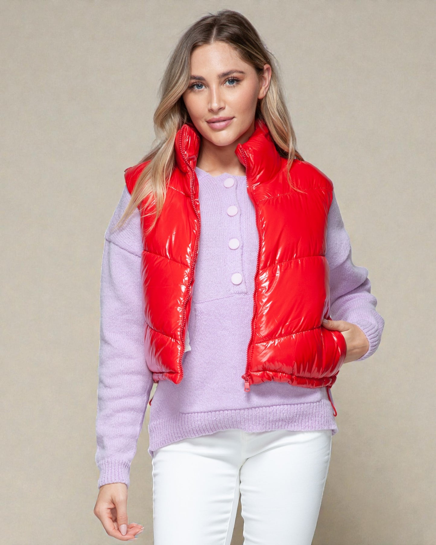 Woman wearing a red puffer vest over a light purple sweater on a beige background
