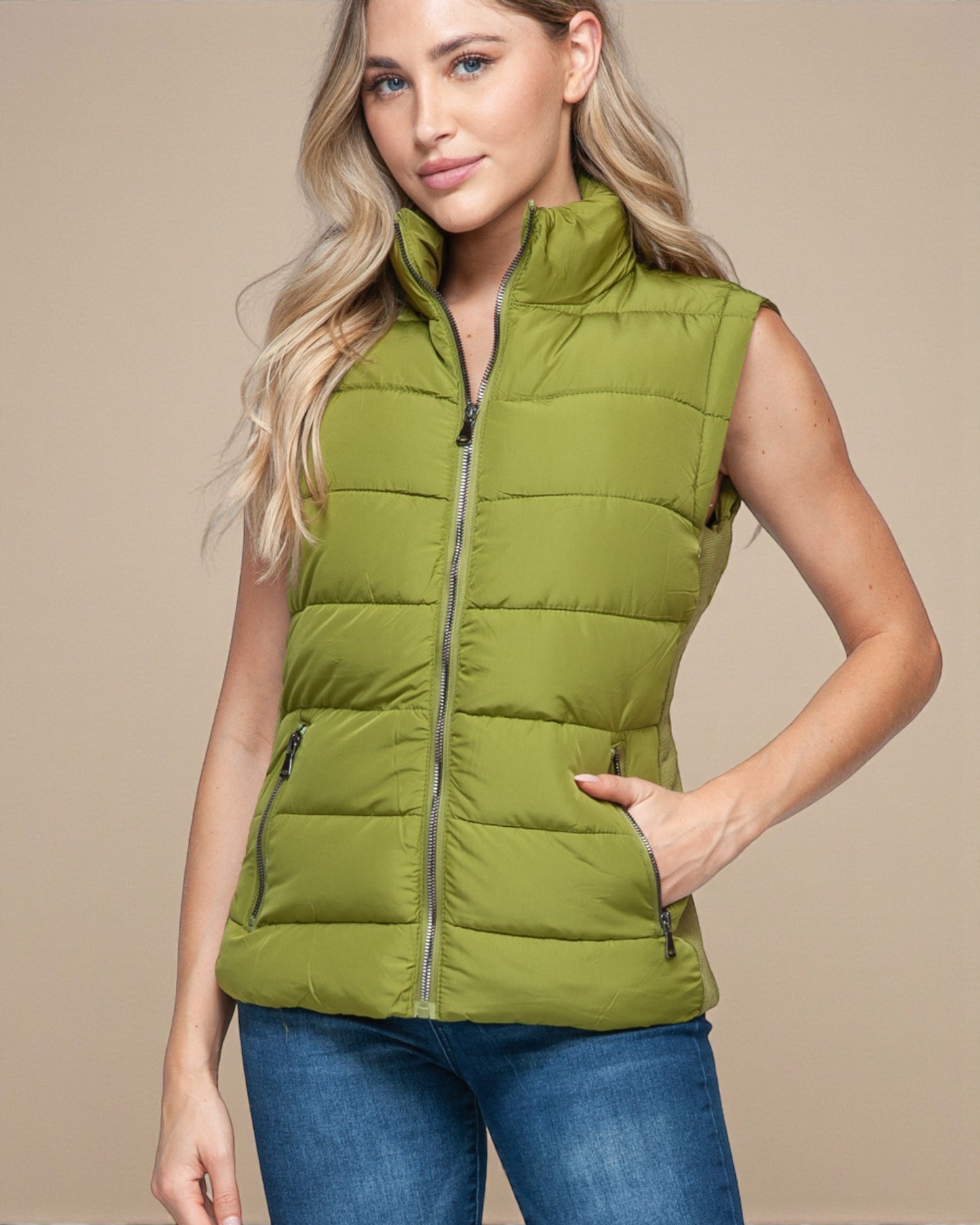 Woman wearing a green puffer vest against a beige background