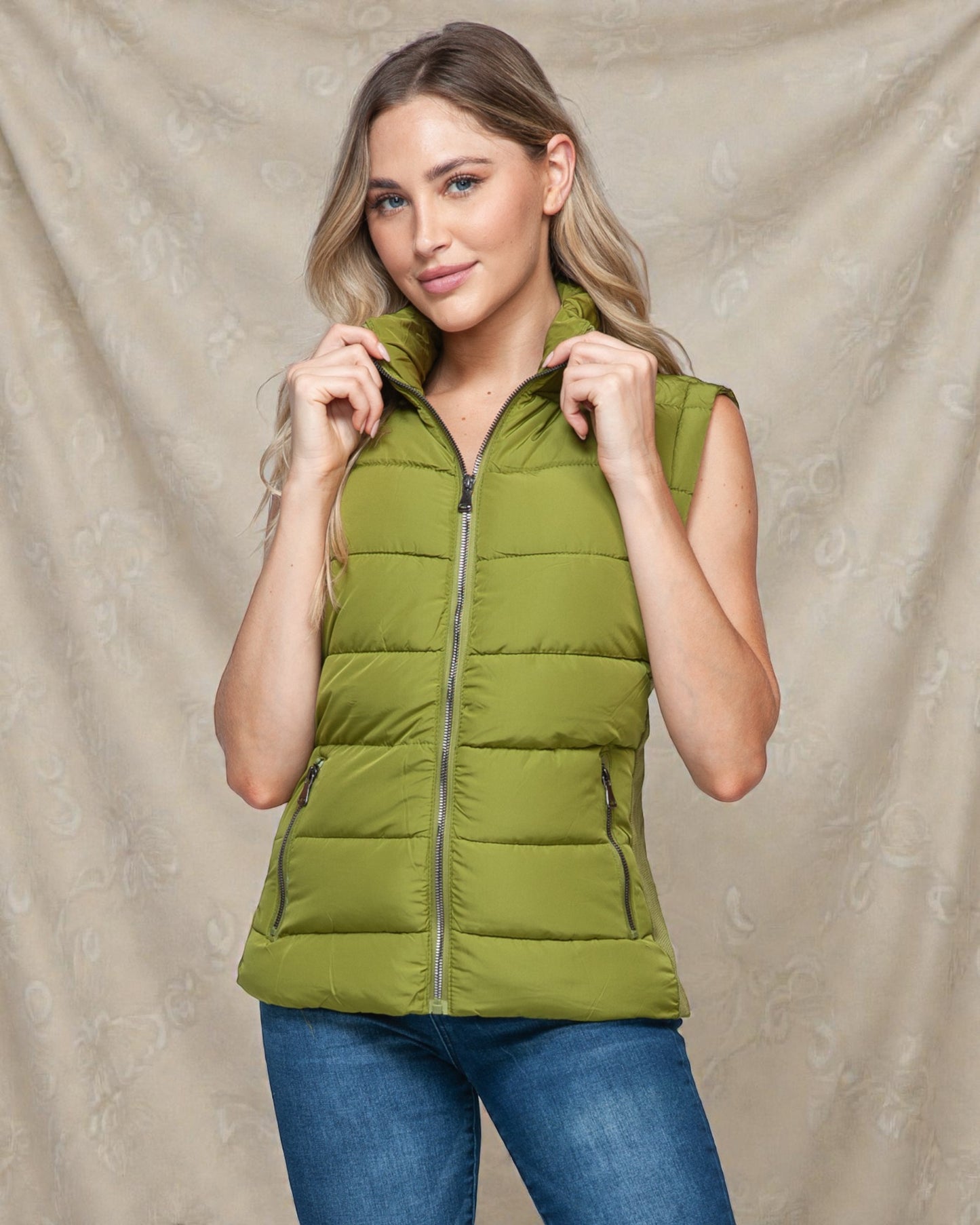 Woman wearing a green puffer vest against a beige background
