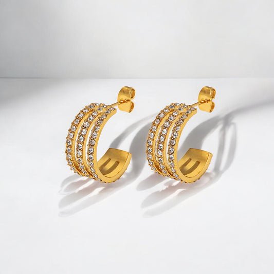 Gold hoop earrings with embedded stones on a light gray background