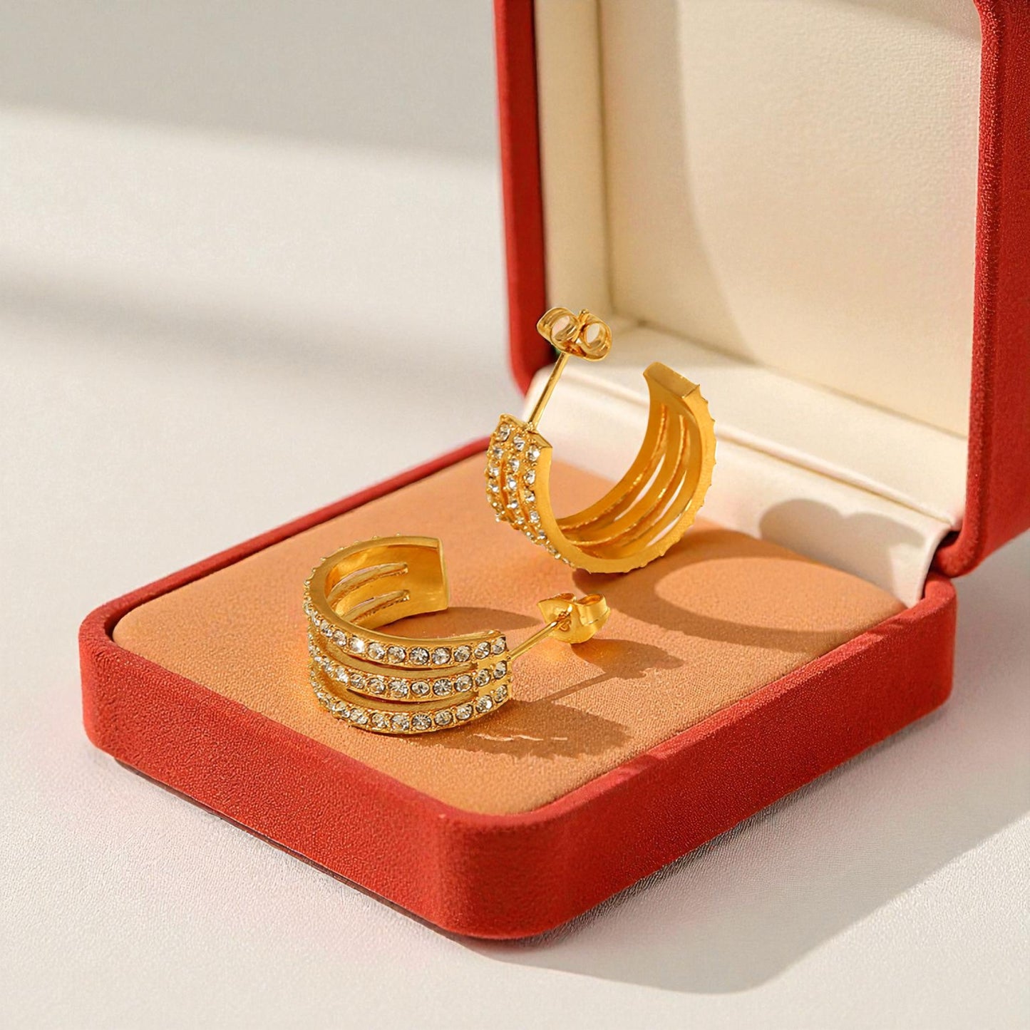 Gold ring and earrings on a red jewelry box with a white background