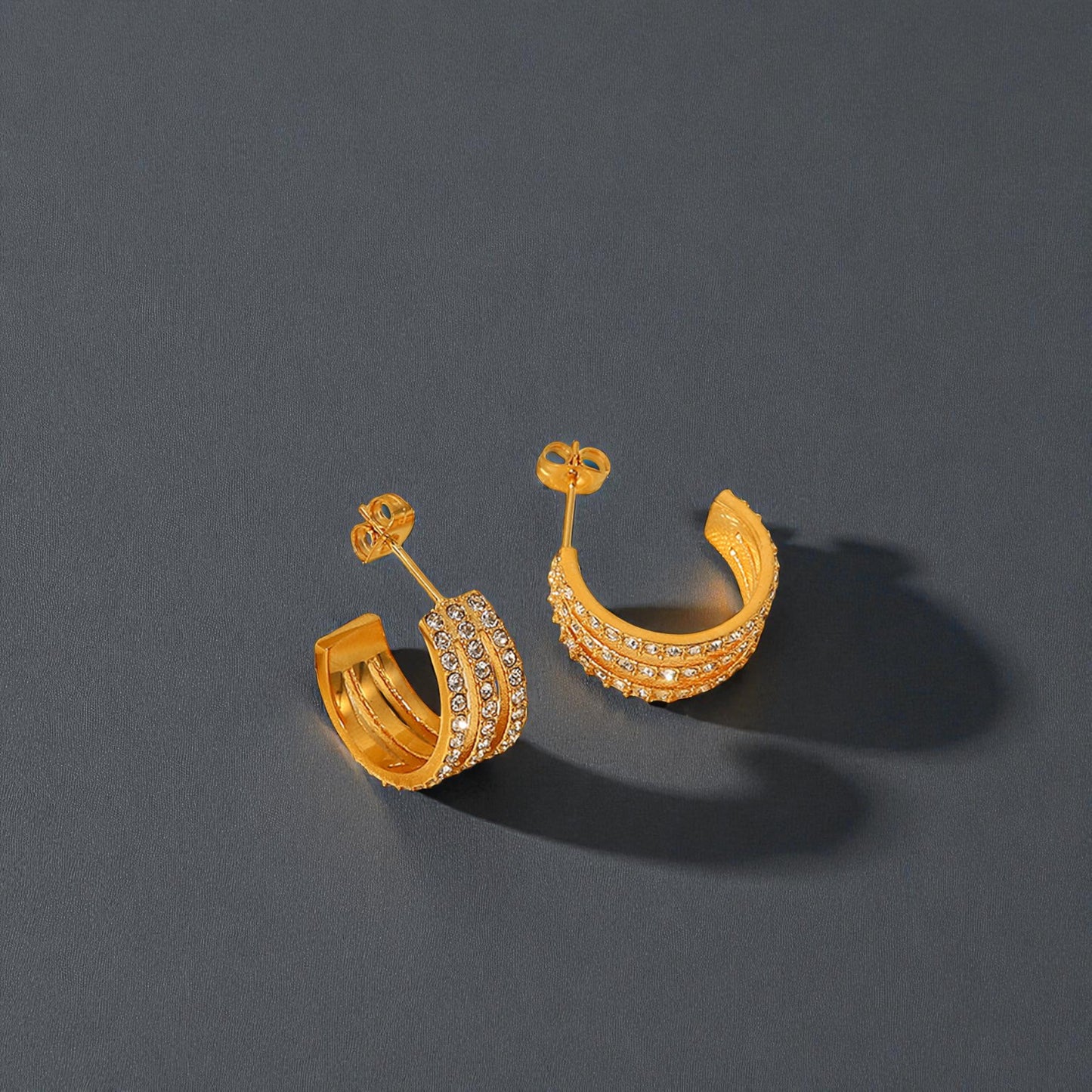 Gold hoop earrings with intricate designs on a dark gray background
