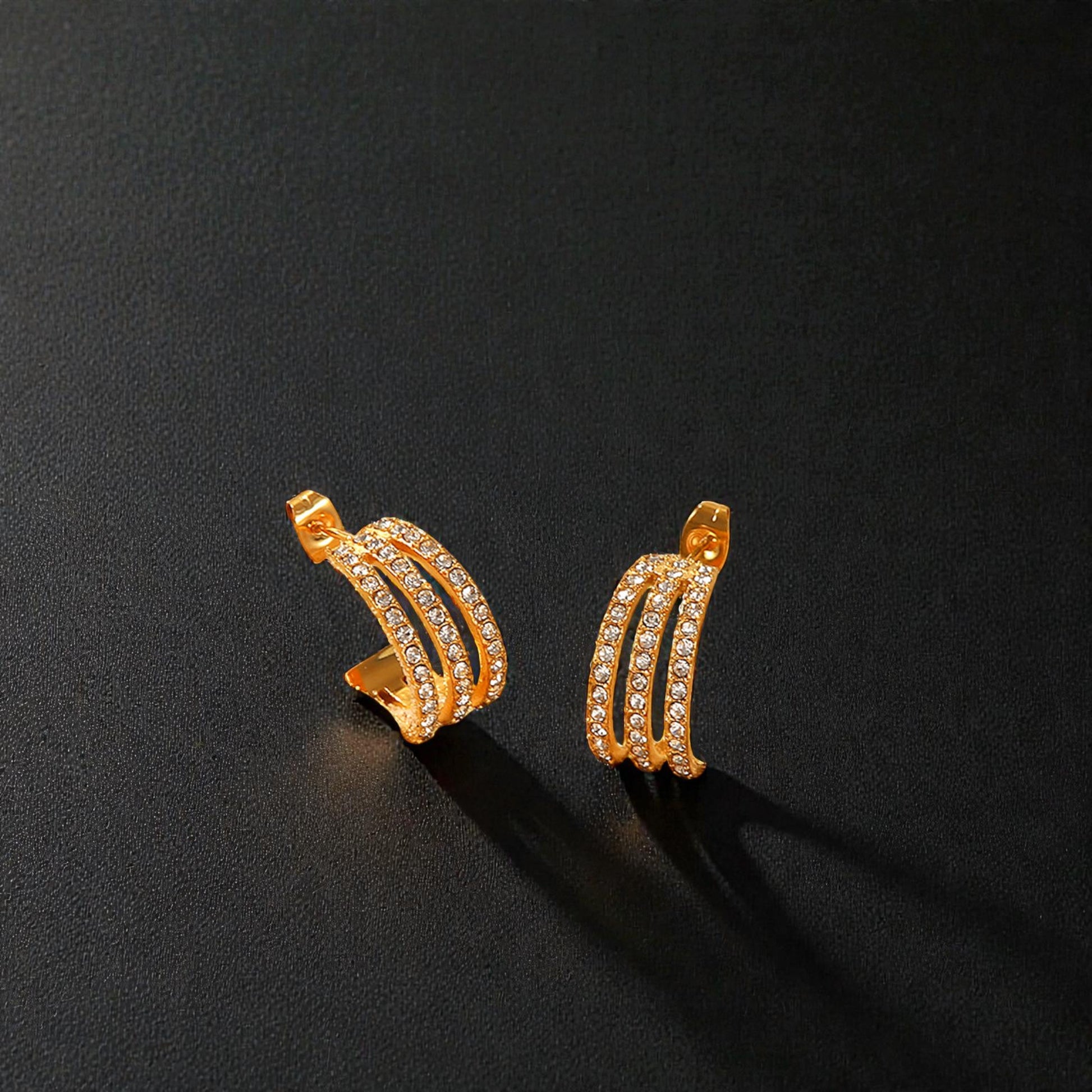 Gold hoop earrings with embedded stones on a black background