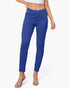 A model wearing a pair of royal blue slim-fit ankle-length pants, paired with a white crop top and clear heeled sandals, against a light gray studio background.