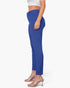 A side-profile view of a model wearing high-waisted, slim-fit royal blue cropped pants with a white crop top and clear high-heeled mule sandals against a plain white background.