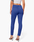 A model shown from the back wearing a pair of royal blue slim-fit ankle-length pants with a button waistband and back pockets, paired with a white crop top and clear high-heeled sandals.
