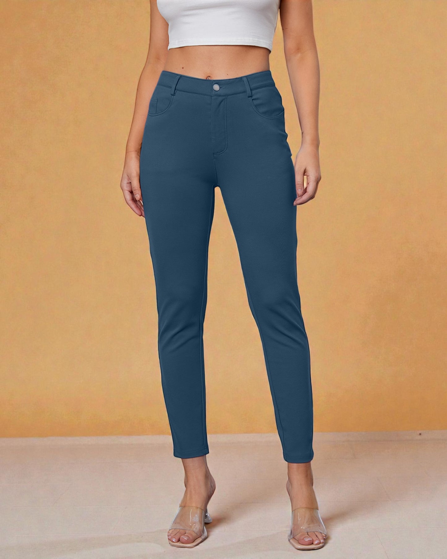 Person wearing teal pants against an orange background