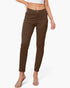 A model wearing slim-fit brown ankle-length pants, paired with a white crop top and clear heeled sandals, against a light gray studio background.