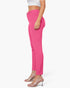 A model shown from the waist down wearing bright pink slim-fit ankle-length pants, a white crop top, and clear high-heeled mule sandals against a plain white background.