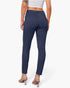 A model shown from the back wearing navy blue slim-fit ankle-length pants, a white crop top, and clear high-heel mules against a light gray studio background.
