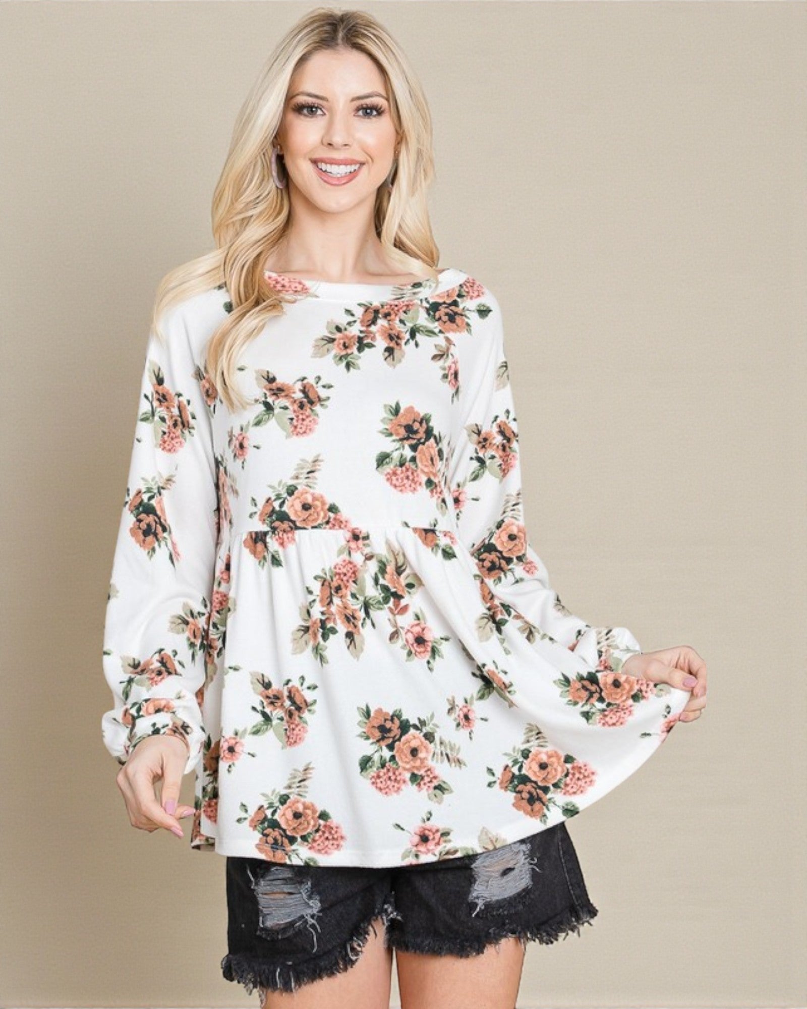 Woman wearing a white floral long-sleeve top with a plain background