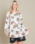 Woman wearing a white floral long-sleeve top with a plain background