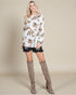 Woman wearing a floral top and knee-high boots on a beige background