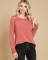 Woman wearing a red long-sleeve top with lace details on a beige background