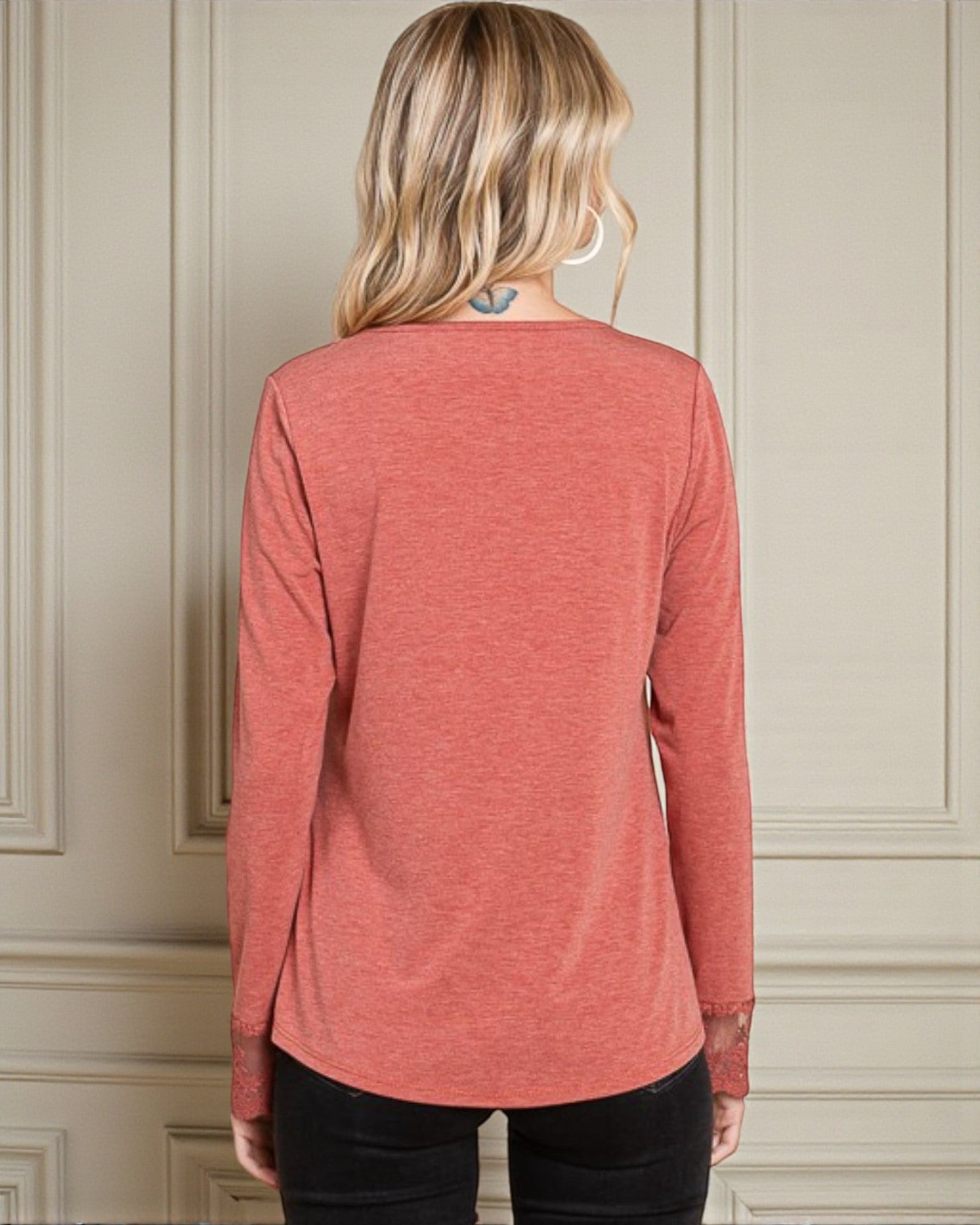 Person wearing a red long-sleeve shirt against a neutral wall.