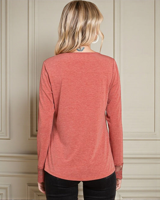 Person wearing a red long-sleeve shirt against a neutral wall.