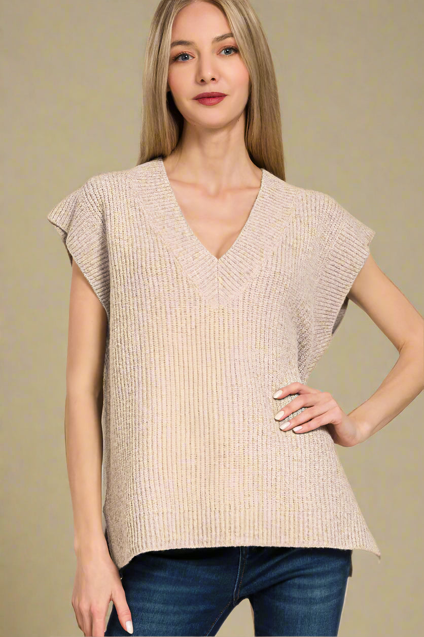 Woman wearing a beige sleeveless top with a plain background