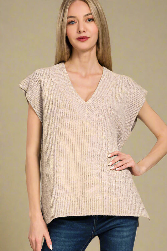 Woman wearing a beige sleeveless top with a plain background